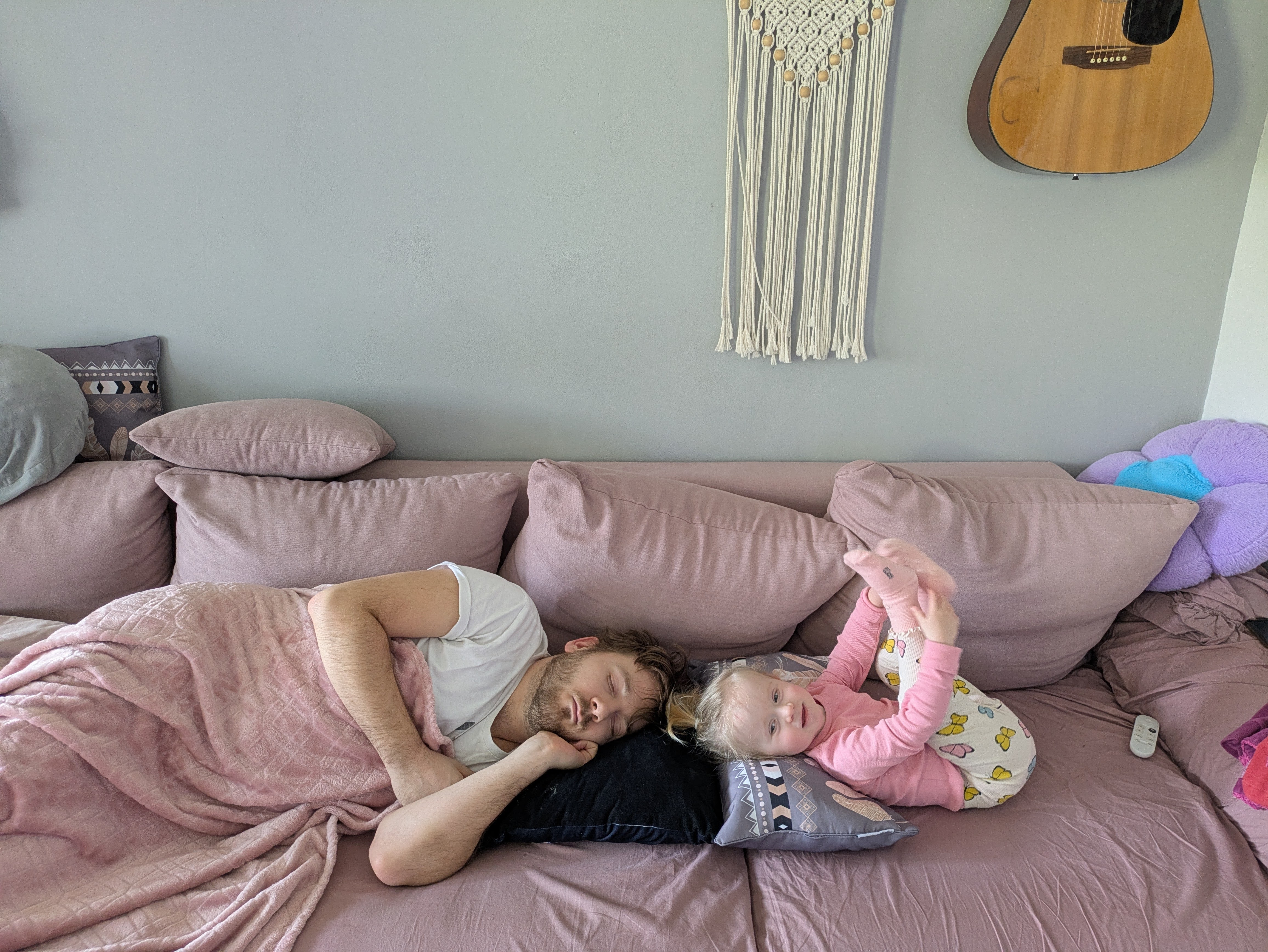 Patrik sleeping on the couch while his daughter plays next to him, a week before surgery