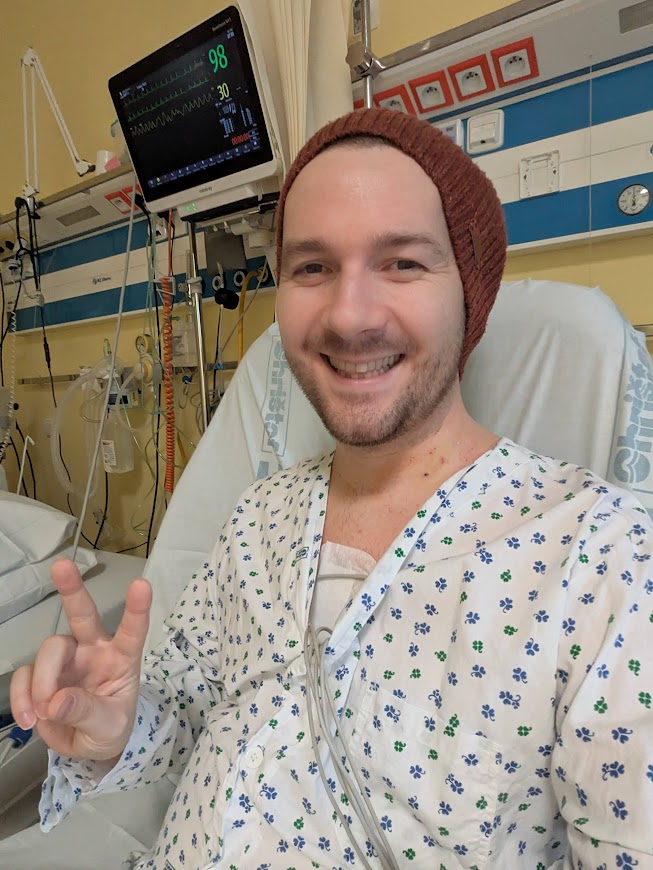 Patrik in hospital after first surgery, giving peace sign